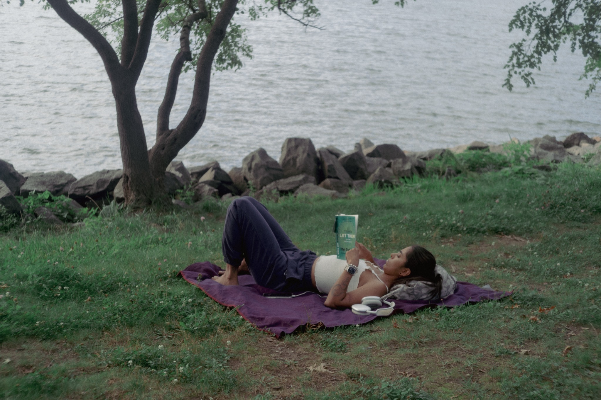 A person reading outdoors by the Hudson River